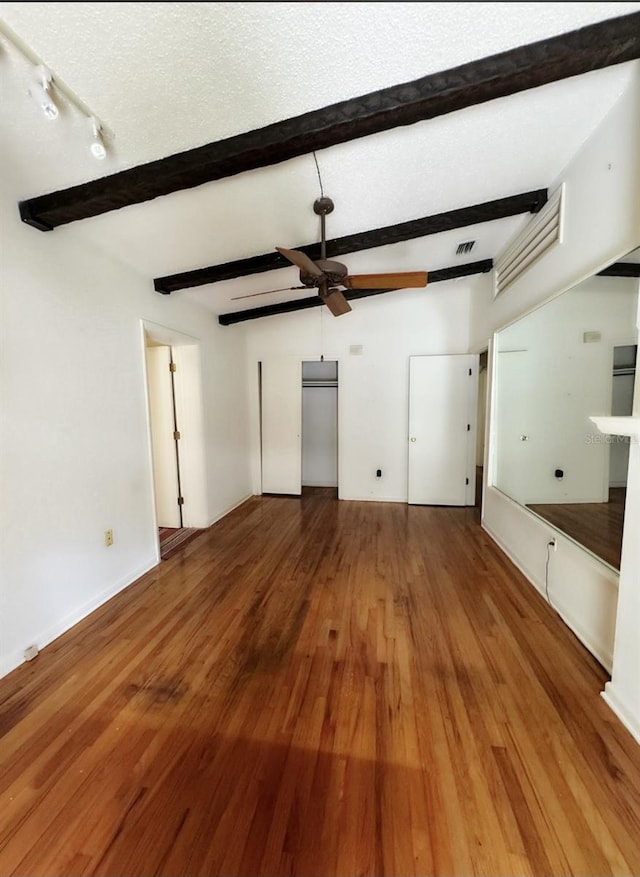 unfurnished living room with ceiling fan, hardwood / wood-style floors, beamed ceiling, and a textured ceiling