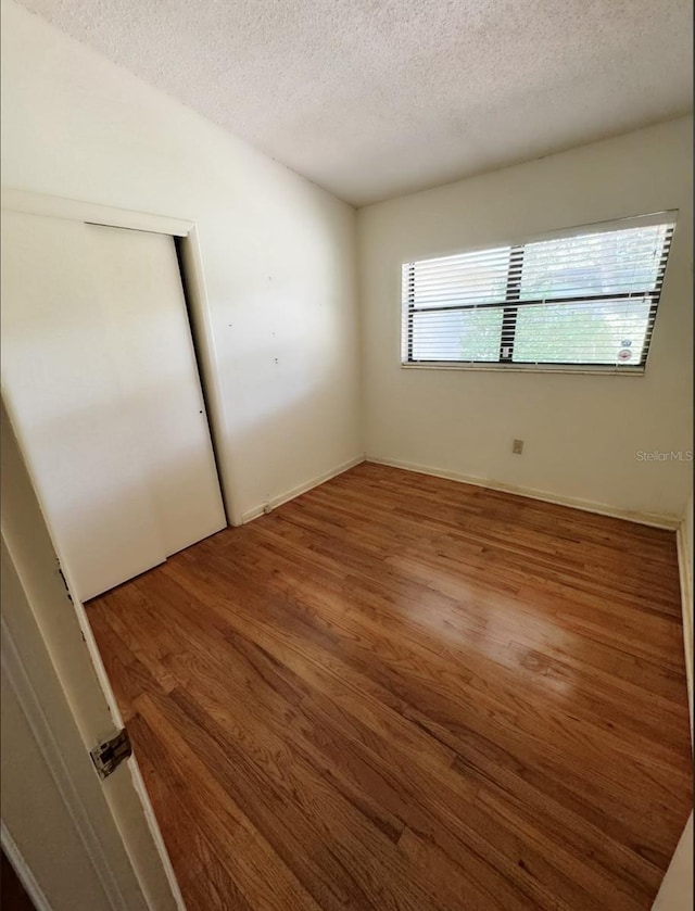 unfurnished bedroom with a closet, wood-type flooring, and a textured ceiling