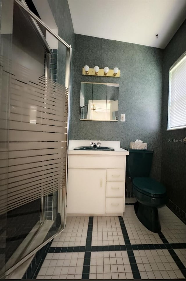 bathroom featuring tile patterned flooring, vanity, a shower with shower door, and toilet