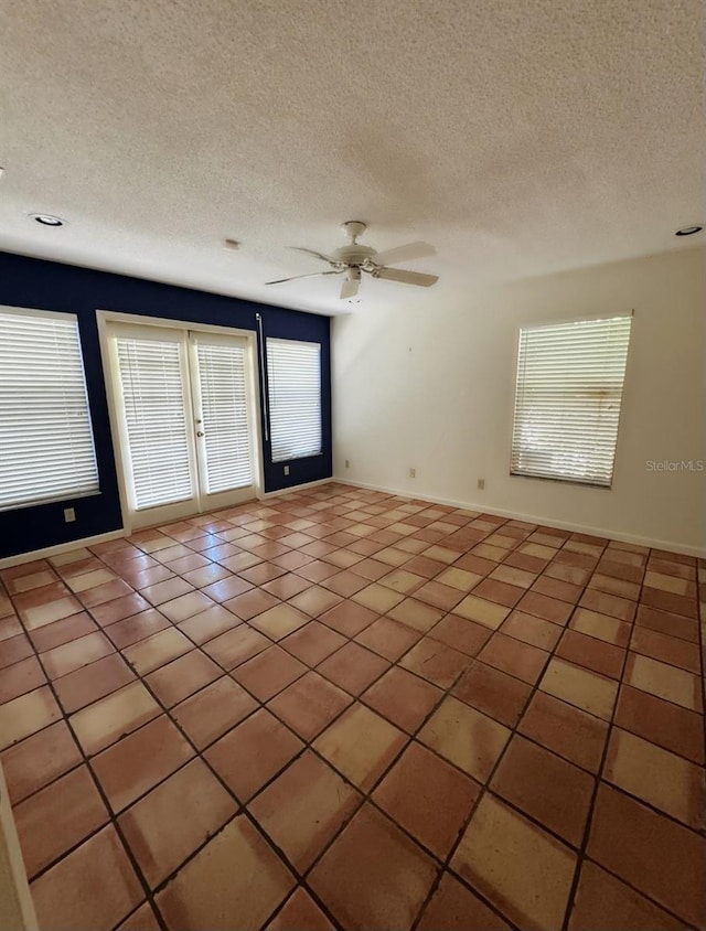 tiled empty room featuring ceiling fan, a textured ceiling, and french doors