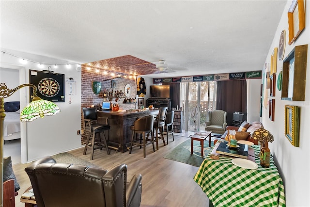 living room with a textured ceiling, ceiling fan, indoor bar, and light wood-type flooring