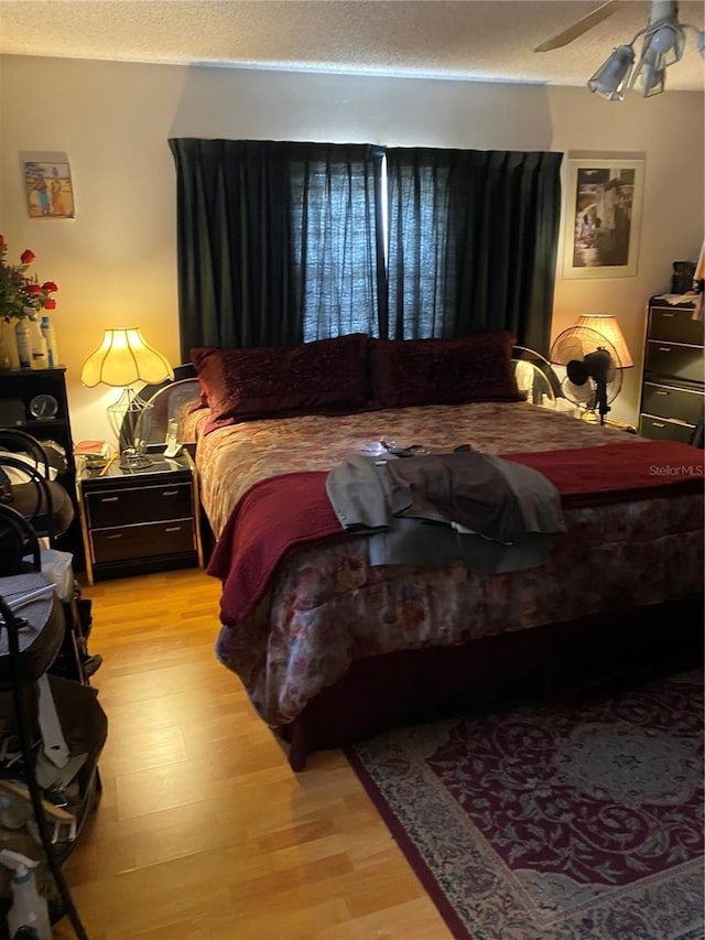 bedroom with a textured ceiling, light hardwood / wood-style floors, and ceiling fan