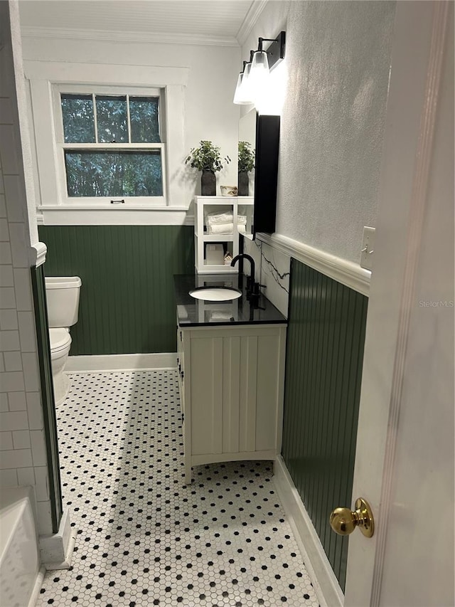 bathroom featuring vanity, a shower, tile patterned floors, crown molding, and toilet