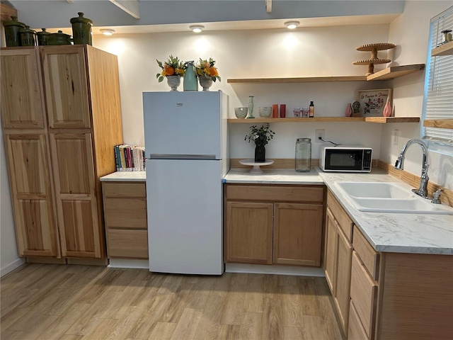 kitchen featuring white refrigerator, light hardwood / wood-style floors, and sink