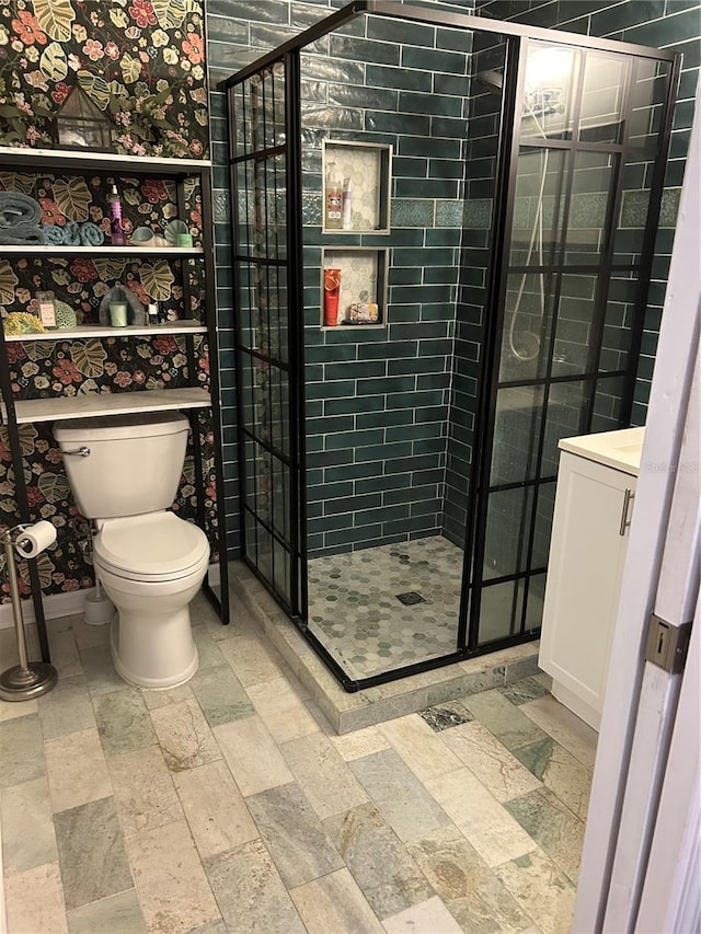 bathroom featuring toilet, a tile shower, and vanity