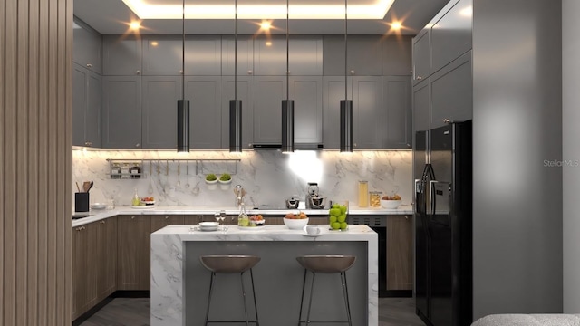 kitchen with a center island, black refrigerator with ice dispenser, a kitchen breakfast bar, decorative backsplash, and gray cabinets