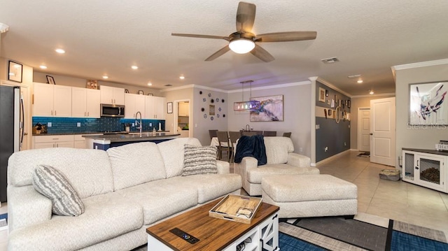 tiled living room featuring ceiling fan, ornamental molding, and sink