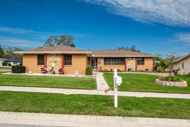 ranch-style home featuring stucco siding, stone siding, and a front yard