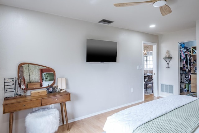 bedroom with a closet, ceiling fan, light hardwood / wood-style flooring, and a walk in closet