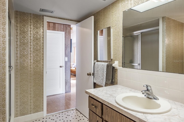 bathroom featuring tile patterned floors, decorative backsplash, vanity, and a shower with shower door