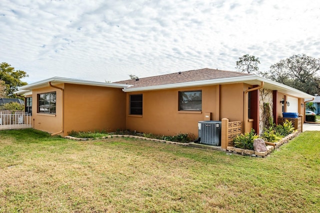 back of property with central air condition unit, a lawn, and a garage