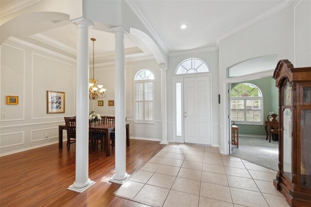 entrance foyer featuring light tile patterned floors, crown molding, and a notable chandelier