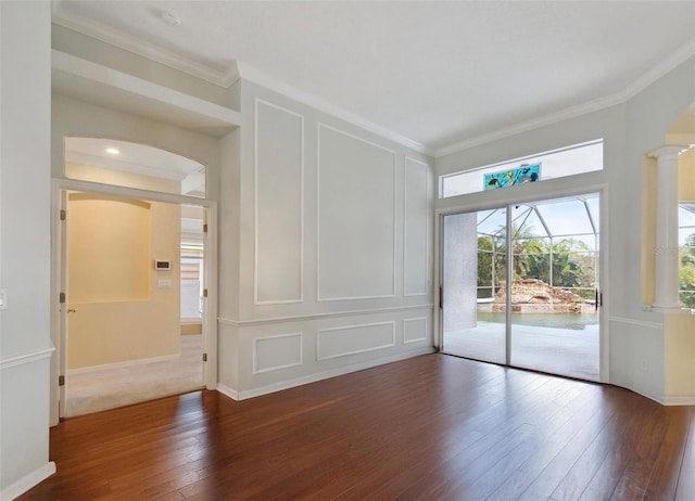 spare room featuring dark hardwood / wood-style floors, decorative columns, and ornamental molding