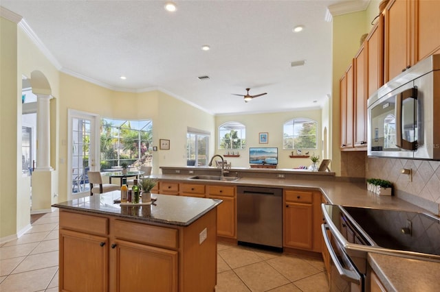 kitchen featuring kitchen peninsula, decorative columns, stainless steel appliances, sink, and light tile patterned floors