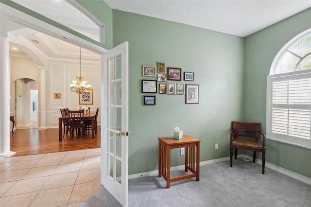 living area featuring decorative columns, french doors, light tile patterned flooring, and an inviting chandelier