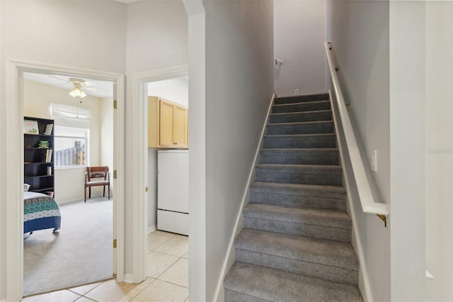 stairway with ceiling fan and carpet floors