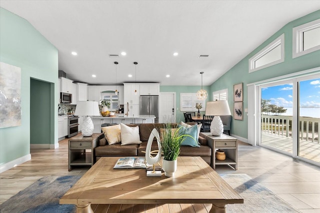 living room with sink, vaulted ceiling, and light hardwood / wood-style flooring