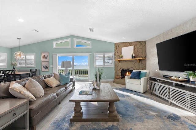 living room featuring hardwood / wood-style floors, a fireplace, a textured ceiling, and vaulted ceiling