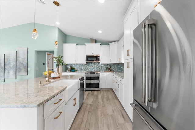 kitchen with pendant lighting, white cabinetry, appliances with stainless steel finishes, and a center island with sink