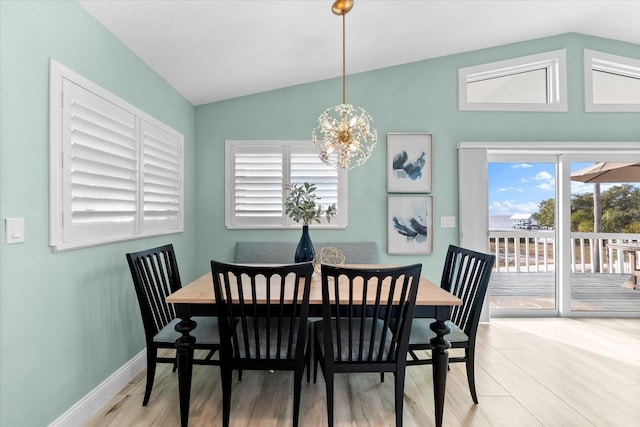 dining room featuring lofted ceiling, light hardwood / wood-style flooring, and a chandelier