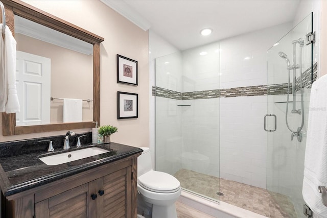 bathroom featuring ornamental molding, toilet, vanity, and a shower with shower door