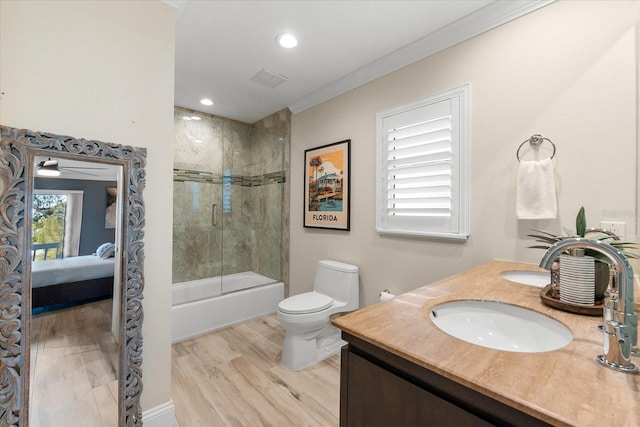 full bathroom featuring hardwood / wood-style floors, shower / bath combination with glass door, vanity, toilet, and crown molding