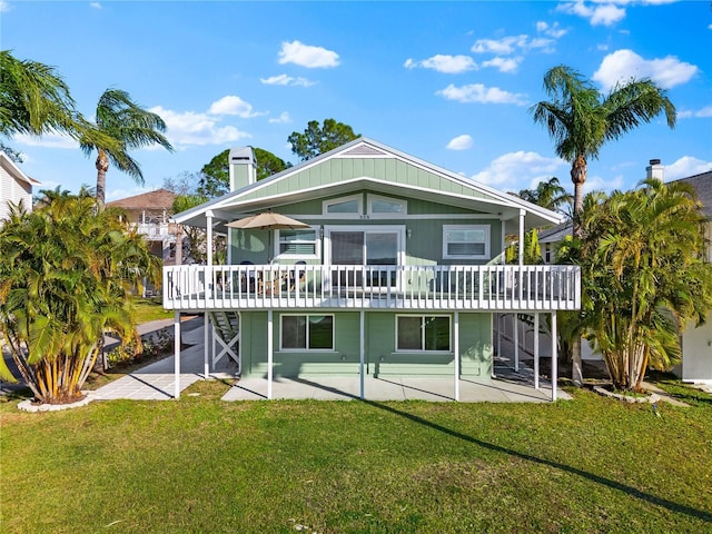 back of property featuring a wooden deck, a patio, and a lawn