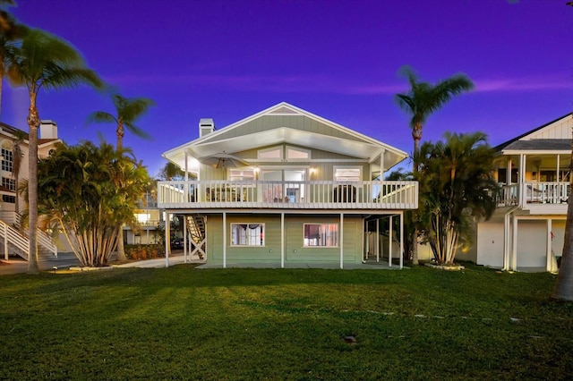 back house at dusk with a wooden deck, a lawn, and ceiling fan