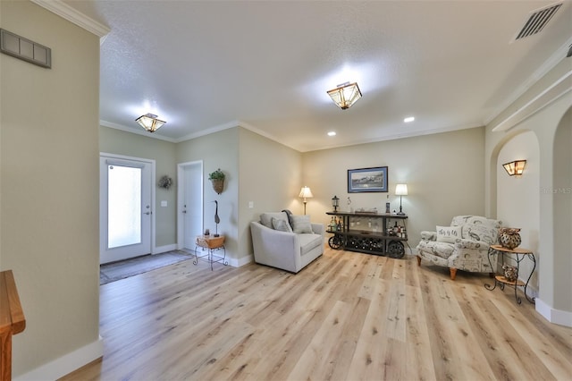 living room with light wood-type flooring, ornamental molding, and a textured ceiling