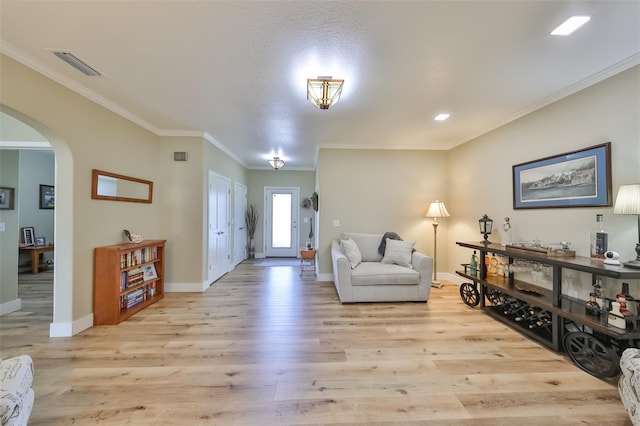 foyer with light hardwood / wood-style floors, ornamental molding, and a textured ceiling