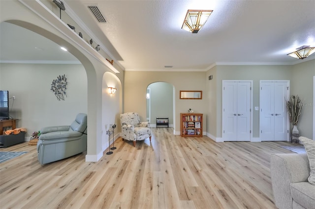 foyer featuring light hardwood / wood-style flooring, a textured ceiling, and ornamental molding