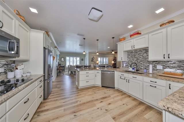 kitchen featuring kitchen peninsula, stainless steel appliances, sink, decorative light fixtures, and white cabinets