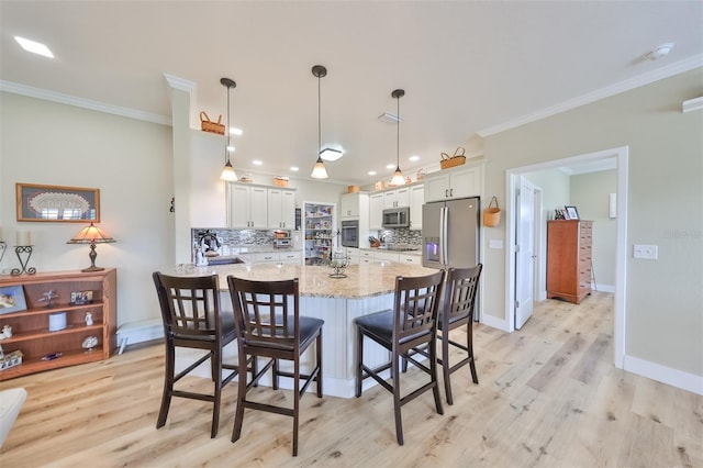 kitchen featuring backsplash, stainless steel appliances, pendant lighting, white cabinets, and light hardwood / wood-style floors