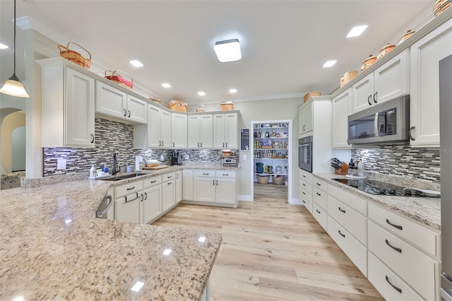 kitchen featuring sink, decorative light fixtures, light stone countertops, wall oven, and light hardwood / wood-style floors