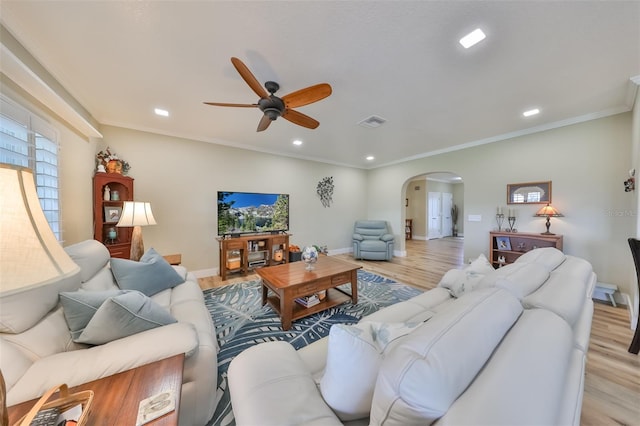 living room with ceiling fan, ornamental molding, and light wood-type flooring