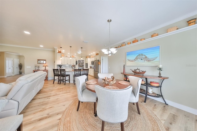 dining area featuring an inviting chandelier, light wood-type flooring, and ornamental molding