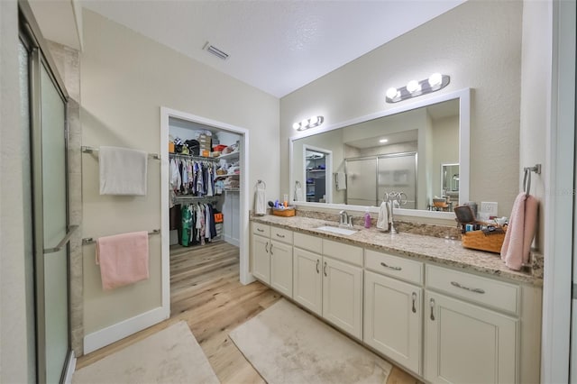 bathroom with hardwood / wood-style floors, vanity, and an enclosed shower