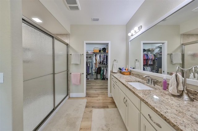 bathroom featuring hardwood / wood-style floors, vanity, and a shower with door