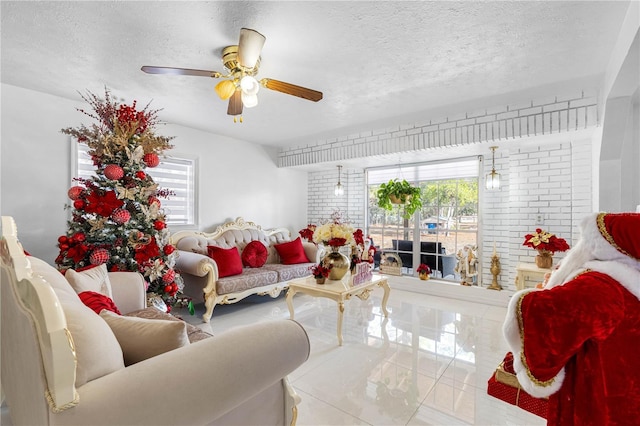 living room with ceiling fan, light tile patterned flooring, and a textured ceiling