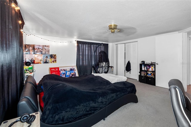 carpeted bedroom with ceiling fan, a textured ceiling, and a closet