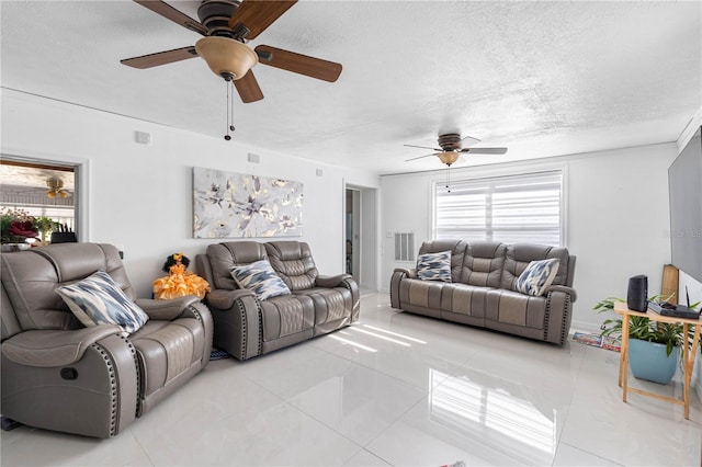 living room featuring ceiling fan, a healthy amount of sunlight, light tile patterned floors, and a textured ceiling