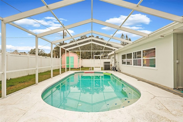 view of swimming pool with glass enclosure, a patio area, and a shed