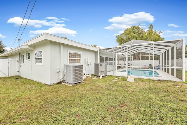 rear view of house featuring a yard, a fenced in pool, glass enclosure, and cooling unit