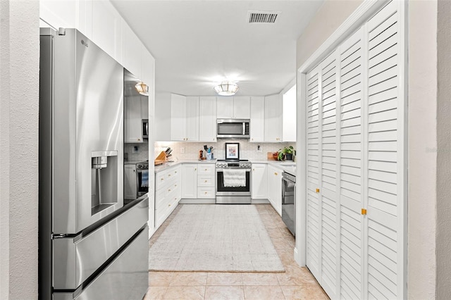 kitchen featuring backsplash, white cabinetry, light tile patterned floors, and stainless steel appliances