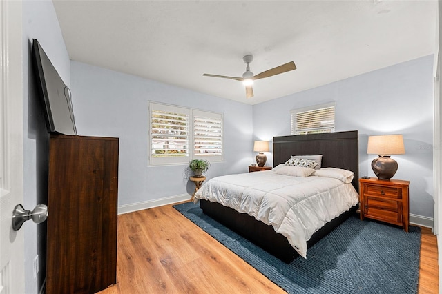 bedroom featuring hardwood / wood-style floors, ceiling fan, and multiple windows