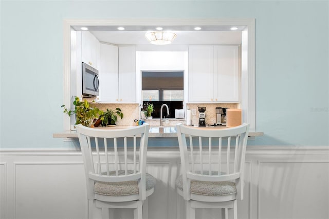 kitchen featuring white cabinetry, sink, and tasteful backsplash