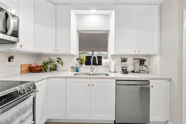 kitchen featuring appliances with stainless steel finishes, backsplash, white cabinetry, and sink