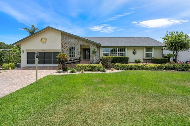 ranch-style house featuring an attached garage, stone siding, decorative driveway, stucco siding, and a front yard