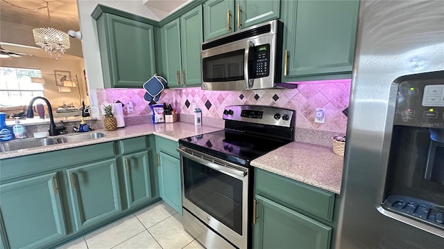 kitchen featuring stainless steel appliances, backsplash, a sink, and green cabinetry