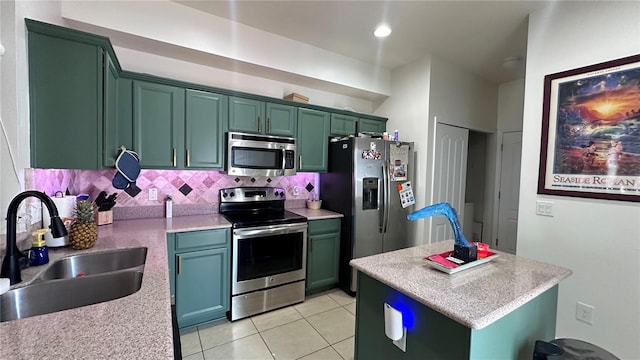 kitchen with light tile patterned floors, green cabinetry, a sink, stainless steel appliances, and backsplash